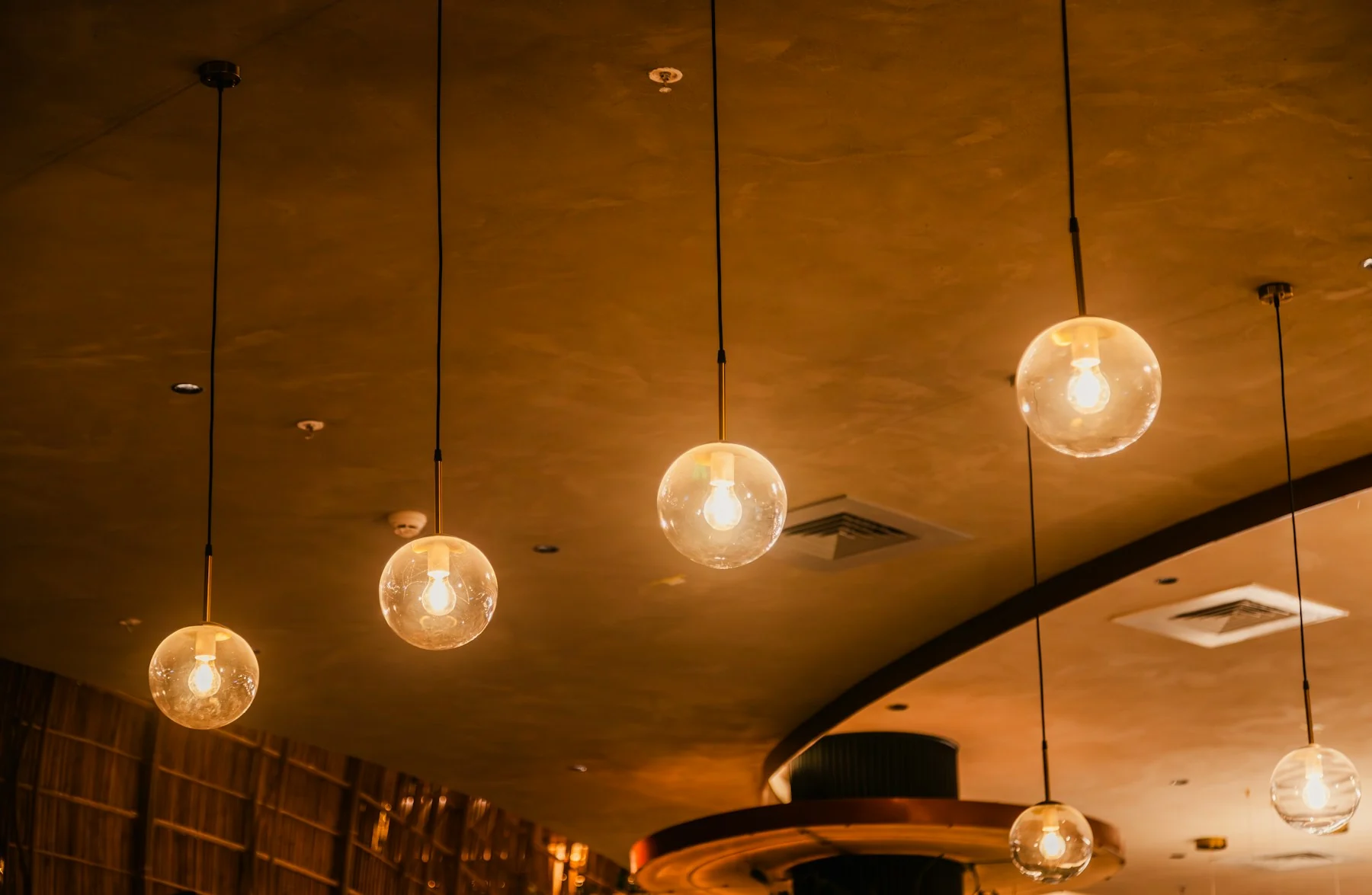Pendelleuchten mit Glasschirmen über einer Restaurantbar
