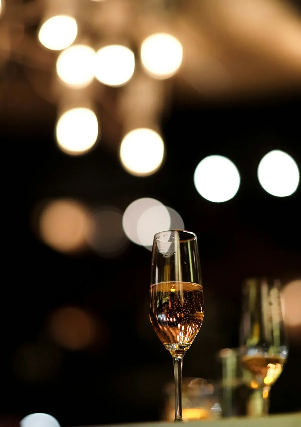 Glas Sekt an der Bar, im Hintergrund warme Lichtpunkte