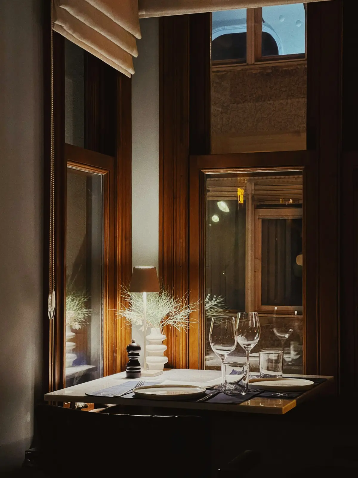 Gedeckter Tisch für zwei an einem hohen Altbaufenster am Abend