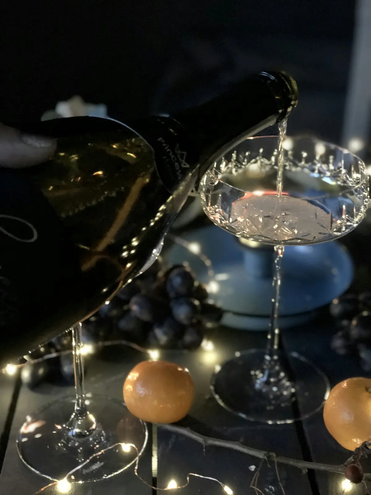 Sekt wird in eine Kristallschale eingeschenkt, kleine Lichter im Hintergrund